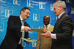 BKu2019s Chairman Board of Directors, Lado Gurgenidze exchange documents with Yves Terracol, the Regional Director of AFD after the signing. Looking on is BKu2019s COO, Lawson Naibo  (Photo T.Kisambira)