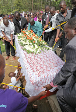 Relatives lower one of the 38 caskets of the victims laid to rest yesterday (Photo T.kisambira