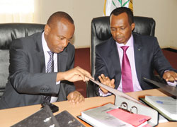 Ambassador Vincent Karega (R)  and the incoming Minister of Infrastracture Albert Nsengiyumva scrutinise documents at the handover ceremony yesterday. (Photo J Mbanda).