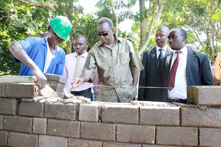A student demonstrates Prime Minister Bernard Makuza how to build