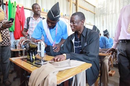 A student shows James Kabarebe the minister of Defense how a sewing machine works