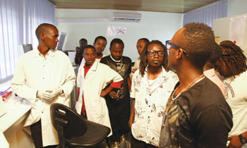 A specialist (in a white laboratory gown) briefs the artists.