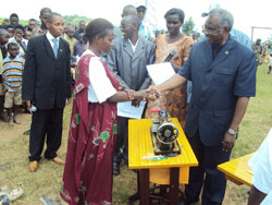 The Minister of Disaster Management and Refugee Affairs Gen. Marcel Gatsinzi hands over a sewing machine to one of the beneficiaries (Photo; JP. Bucyensenge)