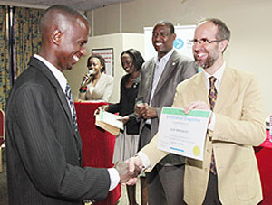 Alex Mwesigwa gets a certificate from Tonny Vetter DOT's senior director, operations as Protais Mitali the Minister of Youth Culture and Sports looks on (Photo T.Kisambira)