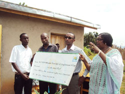 Franu00e7ois Ru00e9gis Gatarayiha (with glasses), the acting Director General of RURA, hands over a cheque of over to Kagitarama Survivoru2019s Association (Photo D Sabiiti.)