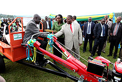 The Governor of the Northern Province, Aime Bosenibamwe (R), congratulates Telesphore Rucibiraro (seated on tractor) who emerged the best farmer during this yearu2019s agricultural expo yesterday, as the Agriculture Minister Dr. Agnes Kalibata hands to him a 