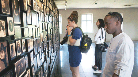 A solemn moment as Eugene Kwibuka(R) and two other journalism students looked at  photographs of victims killed at Auschwitz-Birkenau. (Photo by Suzanne Rozdeba)