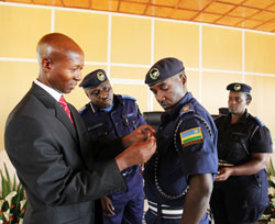 Minister of Internal security, Fazil Harerimana awards a medal to Police Spokesperson, Theos Badege as IGP Emmanuel Gasana looks on, (Photo T.Kisambira)