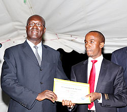 Minister of labour Hon. Anastase Murekezi (L) awards a certificate to Edmond Tubanambazi who was nominated as the best employee in the ministry yesterday 