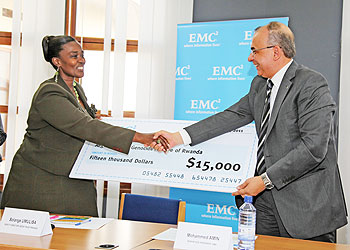 Mohammed Amin (R) the Senior Vice president and Regional Manager of Information Technology company, EMC, hands over a dummy cheque to Solange Umulisa the Deputy Director of AEGIS Trust during a press conference (Photo T. Kisambira)