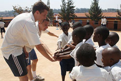 Umubano Project volunteers coach cricket to children. The group has started distributing football kits