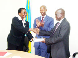 Mary Gahonzire (L) hands over to Paul Rwarakabije as Minister Fazil Harelimana looks on. The New Times Courtsey Photo.