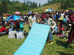 The Karongi District mayor Bernard Kayumba hands over a mattress to one of the VUP beneficiaries The New Times Sam Nkurunziza