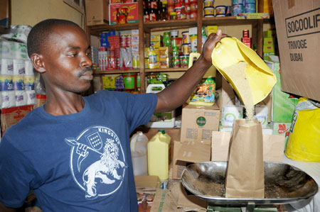  A shop attendant packages sugar at Kigali's Kimironko market yesterday. The price of the commodity has gone down after government's intervention. The New Times/John Mbanda