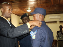 Minister of Internal Security,Musa  Fazil Harerimana,  decorates Frank Bizimungu with the rank of Sergeant as the IGP Gasana looks on. The New Times /Courtesy.