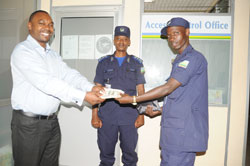 Tanzanian citizen, Rajab Furaj Juma (L), receiving his US$19,700 from police constable Willy Bizimana (R) who picked the money as CSP Felly Bahizi (C) looks on
