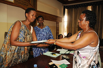 Berrancila Nyinawankusi hands over instruments of power to her successor Alice Ababo as vice Mayor Hope Tumukunde looks on. The New Times /Courtsey Photo