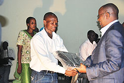 The Minister of Local Government James Musoni hands over a laptop to a local leader. The government wants grassroots leaders to use computers. The New Times / file photo
