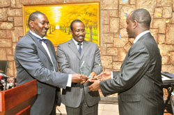 From L-R President-elect of SMACKBA, Ebert Byenkya, Joseph Kitamirike, CEO of Uganda Securities Exchange (C) present an award to the SG of EAC Dr Richard Sezibera.