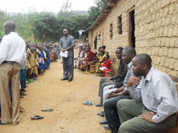 Felix Ugrimbabazi (R) seated with some parents as the Ecole Primaire Busake headmaster Malachie Birege addresses pupils in front of their classrooms. The New Times  / Grace Mugoya