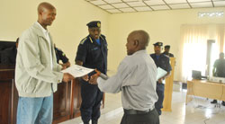 The Minister of Internal Security, Sheik Musa Fazil Harerimana, presents a certificate of service to a retired police officer. On his left is Police boss Emmanuel Gasana
