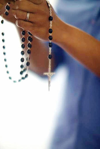 Close up of hand holding rosary beads. Net Photo