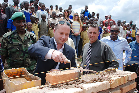 Oleg Moiseev, the MD of Rogi, a mining company that is exploring gold in the Northern Province, lays a brick at a school construction site in Burera District yesterday. The firm donated Rwf6 million to two schools towards the construction of extra classro