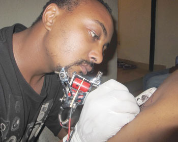 Eric uses the sophisticated tattoo machine to shade a client. The New Times / D. Umutesi