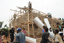 People offer help to put up a house belonging to a poor family during the campaign against grassthatched houses. The New Times / File