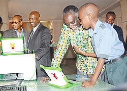 Jean Luc Nsabimana (R) takes senator Tito Rutaremara through the wonders of ICT as Senator Laurent Nkusi (L) and the OLPC coordinator, Nkubito Bakuramutsa, admire ICT tools at Parliament yesterday. The New Times / J. Mbanda.