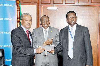 Makonnen Negatu, ADBu2019s country representative (L) exchanges documents with James Gatera, BK Managing Director as central bank Governor, Claver Gatete looks on (Courtesy photo).