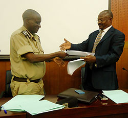 The Commissioner General of RCS, Paul Rwarakabije exchanging documents with the Deputy CG of UPS, James Mwanje after signing partnership agreements.  The New Times/ courtesy.