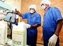 Workers package flour at local milling firm MINIMEX. The milling company currently purchases maize from Tanzania. The New Times / Timothy Kisambira.