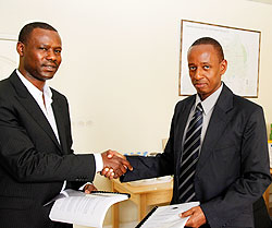 Egide Gatera (L), Chairman Rwanda Mountain Tea, exchanging documents with Eugene Haguma, the CEO of Horizon Group. The New Times / Timothy Kisambira.
