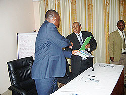 ICPA Rwanda president Peter Rutaremara (L) exchanges documents with OCCARChairman, Charles Karara shortly after signing the partnership MoU. The New Times / File