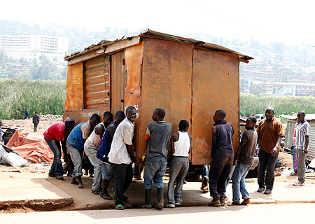 Porters carrying one of the containers that worked as makeshift spare parts shops from the vacated garage yard in Gatsata. The place has been vacated.  The New Times / T. Kisambira