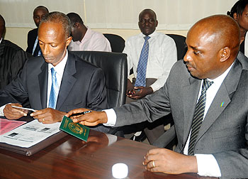 Director General of Immigration and Emigration Anaclet Kalibata (L) and National ID Coordinator Pascal Nyamulinda examine the new travel document at its launch on Tuesday. The New Times / File