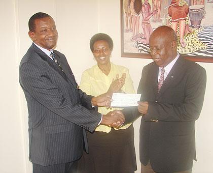 Rwanda's High Commissioner to Uganda Frank Mugambage hands over a cheque to Igongo Centre boss James Tumusiime yesterday. The New Times / G. Muramira
