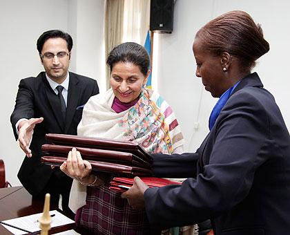 The Indian State Minister for External Affairs Preneet Kaur (c) exchanges documents with Foreign Affairs Minister, Louise Mushikiwabo  yesterday. The New Times / T. Kisambira.