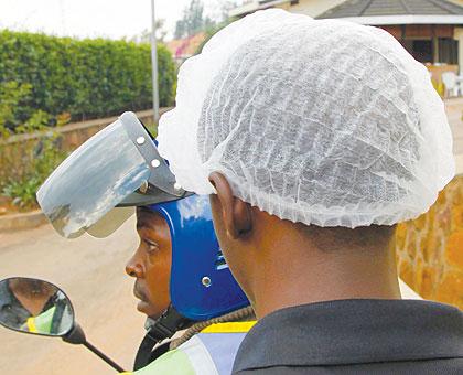 A passenger wearing a smart cover, which is normally placed beneath a helmet. The headgear has been reintroduced and made compulsory as a hygienic measure. The New Times / File.