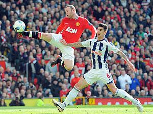 Wayne Rooney (L) vies for the ball with West Bromu2019s Liam Ridgewell during the English Premier League football match yesterday. Net Photo.