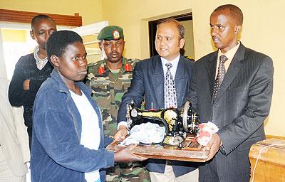 Verene Mushimiyimana (L) receives a sewing machine from Gisovu Tea Factory Manager, Surender Jhijaria  (C), and Karongi District Mayor, Bernard Kayumba. The New Times / John Mbanda.