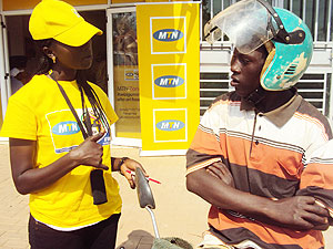 An MTN staff explaining to a motocyclist about the company services. The New Times / File.