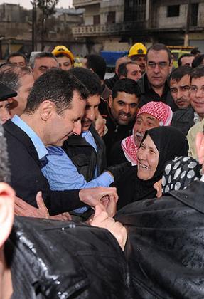 President Bashar al-Assad (L) greets his supporters during his visit to the Baba Amr neighbourhood in the restive city of Homs on March 27. Net photo.