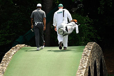 Tiger Woods of the US and his caddie cross a bridge during the first round of the 76th Masters golf tournament at Augusta National Golf Club.