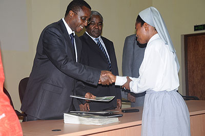 The Minister of Education, Dr Vincent Biruta, gives Crescence Uwarurema her transcripts as KIE Rector, Prof George Njoroge looks on.  The New Times / Grace Mugoya.