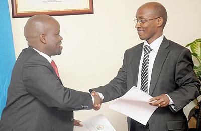Minister of Youth Jean Philbert Nsengimana (L) and Ignace Gatare shake hands at the handover ceremony on Tuesday following the transfer of ICT portfolio to the Ministry of Youth. The Sunday Times/ John Mbanda