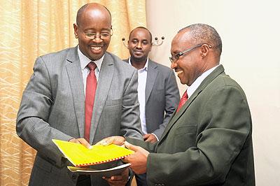  Ministers Protais Musoni (R) and James Musoni exchange documents at the handover ceremony transferring the media docket from the Ministry for Cabinet Affairs to the Ministry of Local Government.  The Sunday Times/ John Mbanda