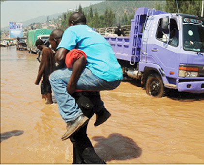 A man is carried across the flooded Nyabugogo highway.  The New Times / File.