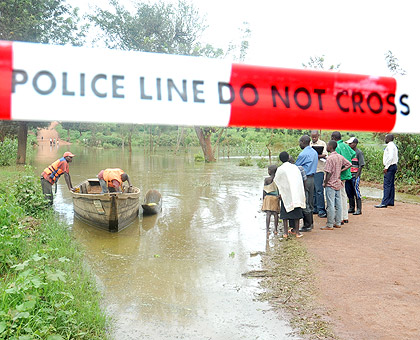 END OF THE ROAD; Stranded people wait for a canoe to cross to Masaka yesterday.  The New Times / J. Mbanda